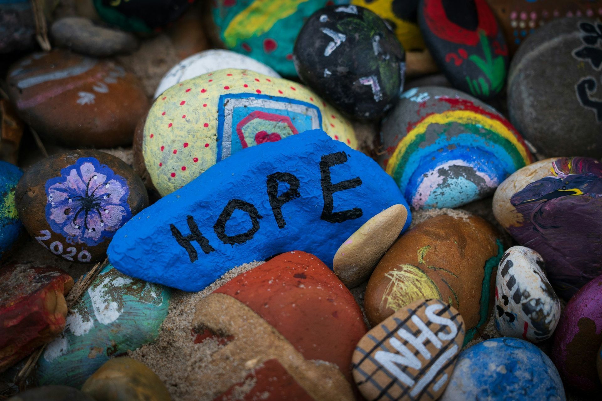 Painted stones with “HOPE” in blue among colorful pebbles