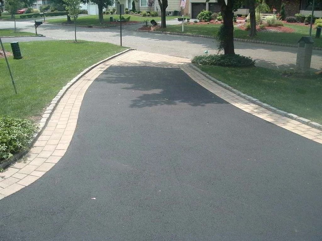 Curved paved park path bordered by grass and trees on a sunny day