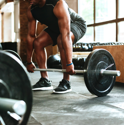 A man is lifting a barbell in a gym