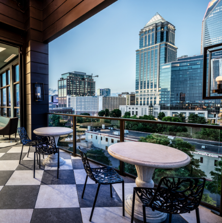 A balcony with tables and chairs overlooking a city