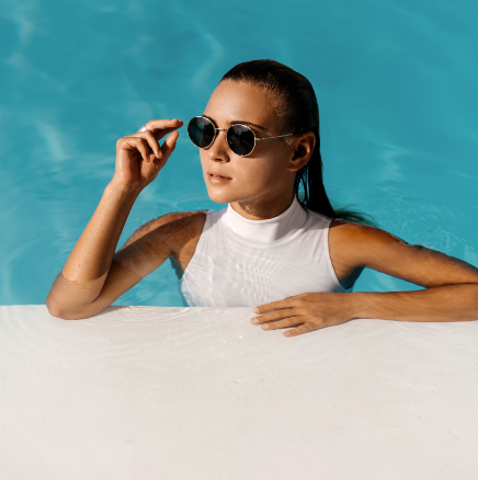 A woman wearing sunglasses is swimming in a pool