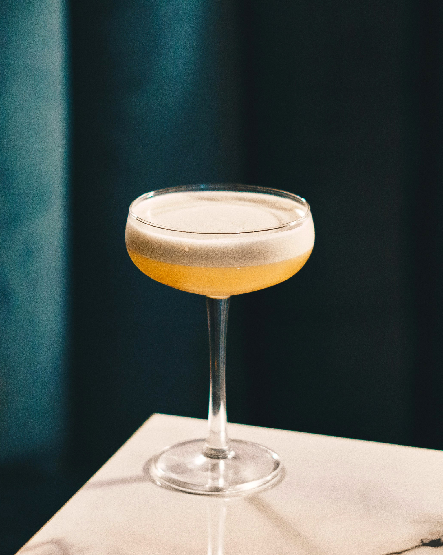 A close up of a cocktail in a coupe glass on a table.