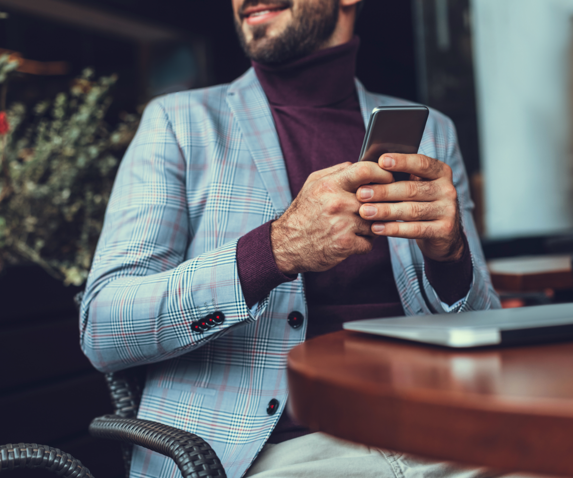 A man is sitting at a table looking at his cell phone.