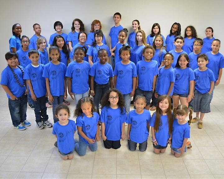 A large group of children wearing blue shirts are posing for a picture