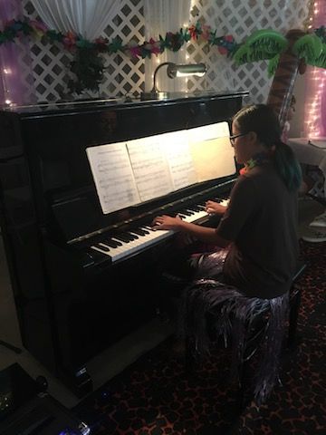 A woman is playing a piano in a room.