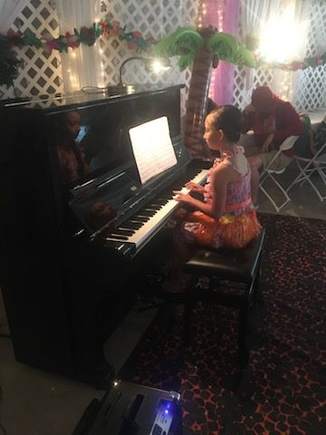 A little girl is playing a piano in a room.