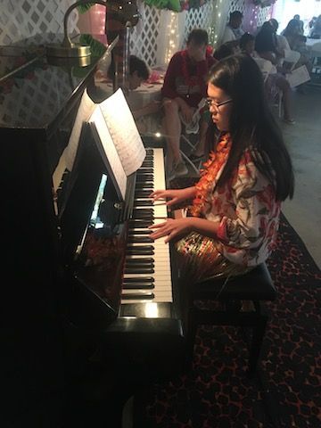 A woman is playing a piano in a room.
