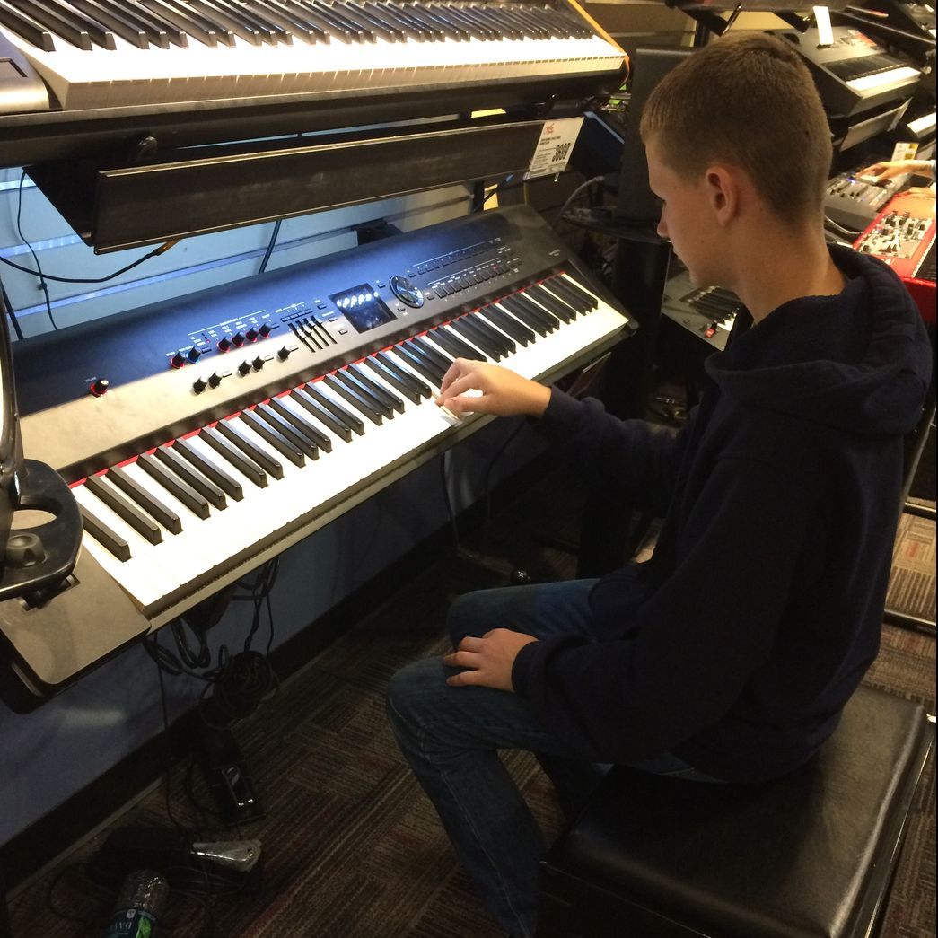 A young boy is playing a keyboard in a room