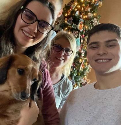 A group of people are posing for a picture with a dog in front of a christmas tree.