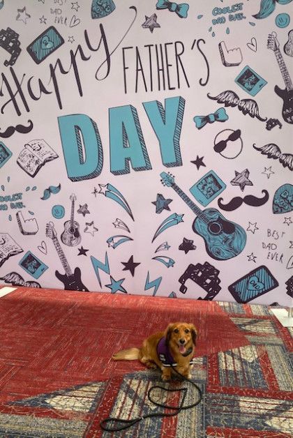 A dog sitting in front of a wall that says happy father 's day