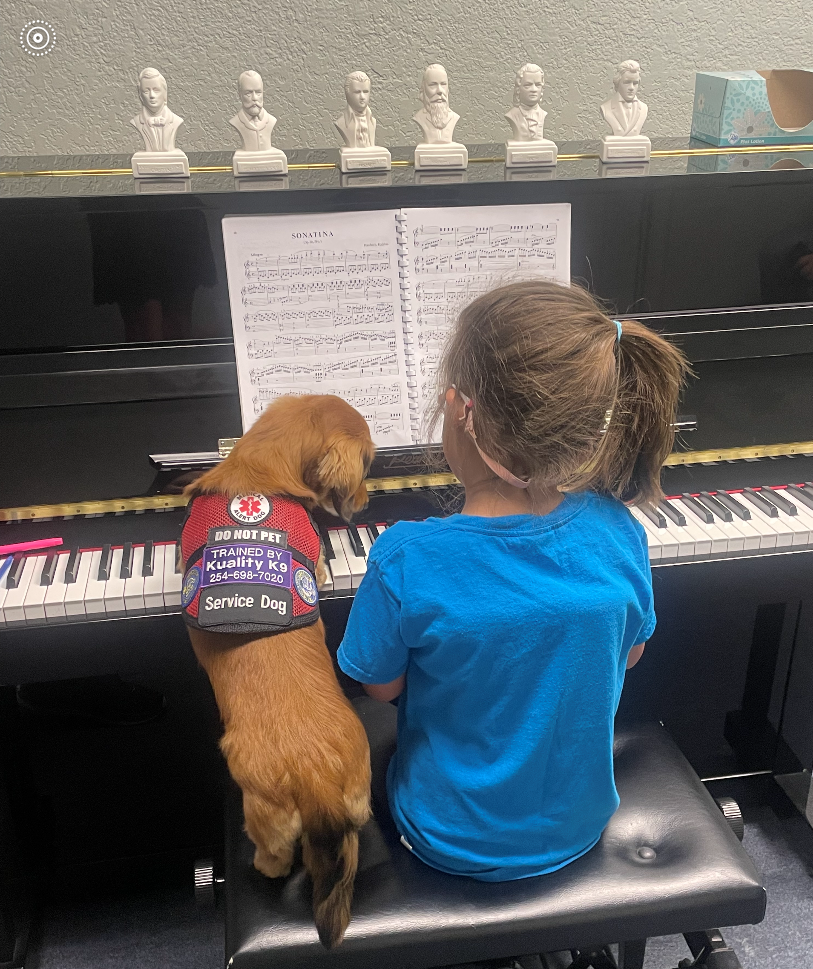 A girl and a dog are playing a piano together.