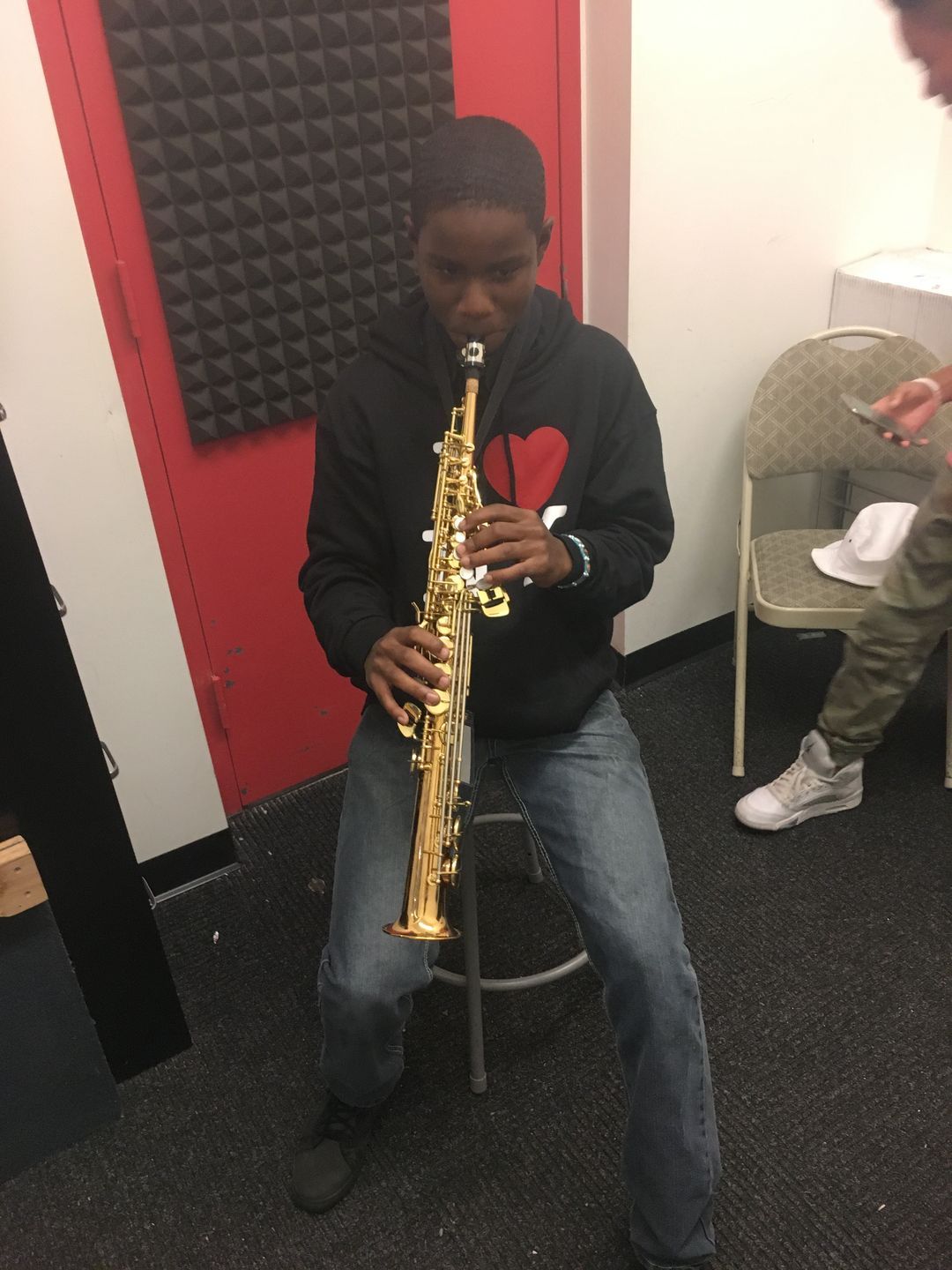 A young boy is playing a saxophone in a room