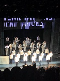 A group of men are standing on a stage in front of a sign that says ' lenin ' on it