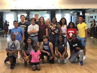 A group of people are posing for a picture in a dance studio.