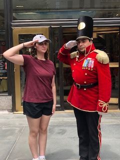 A woman is saluting next to a man in a red uniform.