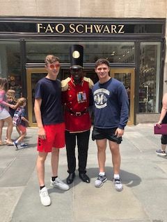 Three young men are posing for a picture with a toy soldier in front of a building.