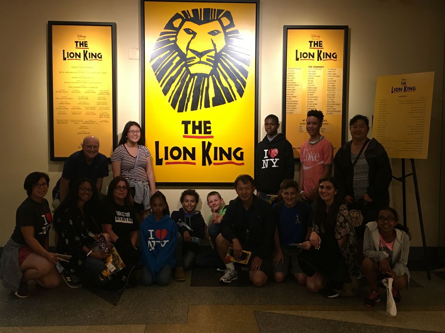 A group of people posing in front of a lion king poster