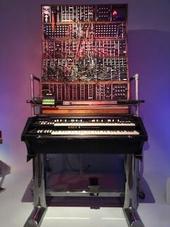 A keyboard is sitting in front of a wall of electronic equipment.