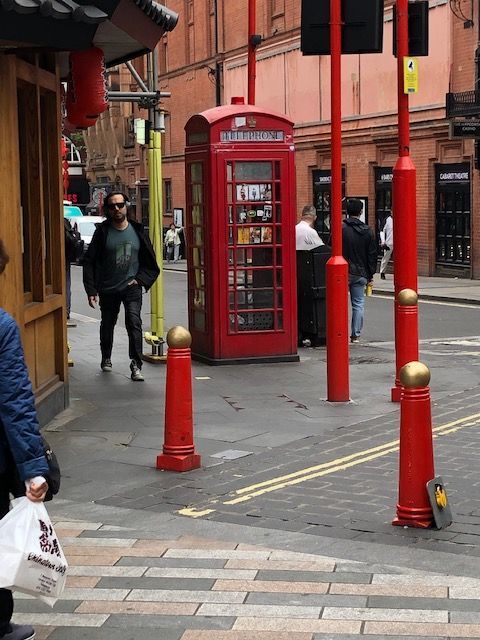 A red telephone booth on the side of a street