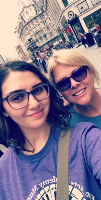 Two women wearing sunglasses and purple shirts are posing for a picture