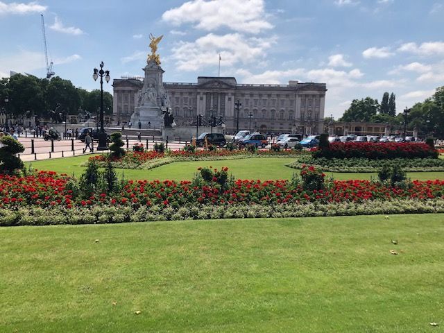 A large building with a statue in front of it is surrounded by flowers and grass.