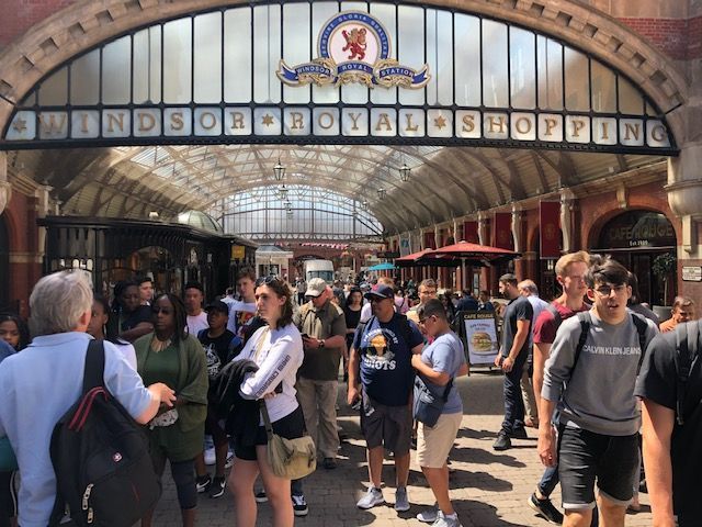 A crowd of people are gathered under a sign that says 