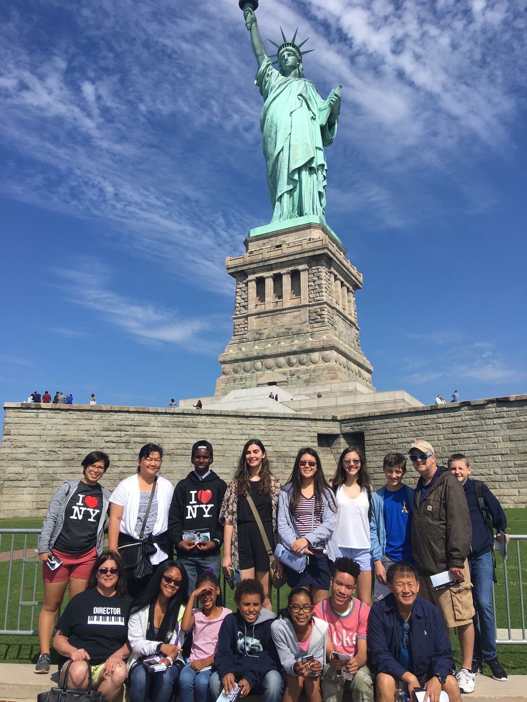 A group of people are posing for a picture in front of the statue of liberty.