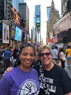 Two women are posing for a picture in front of a city street.
