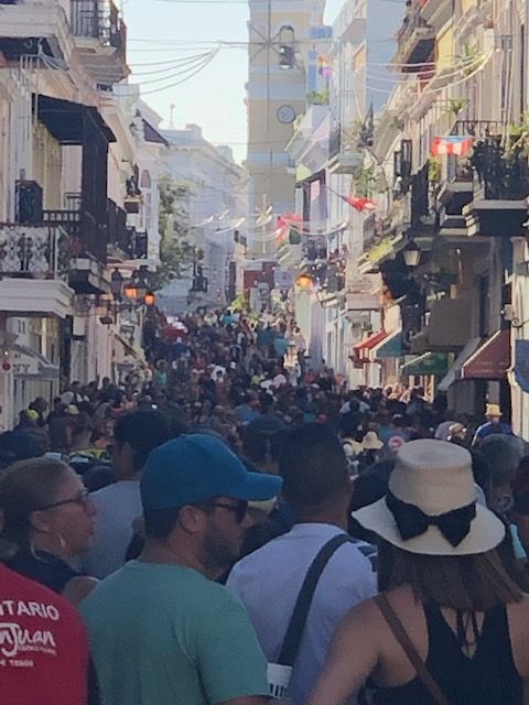 A crowd of people walking down a street with a man wearing a red shirt that says ontario