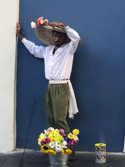 A man wearing a sombrero is holding a basket of flowers