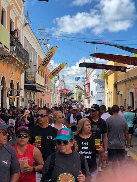 A woman wearing a shirt that says let 's drink our walks down a crowded street