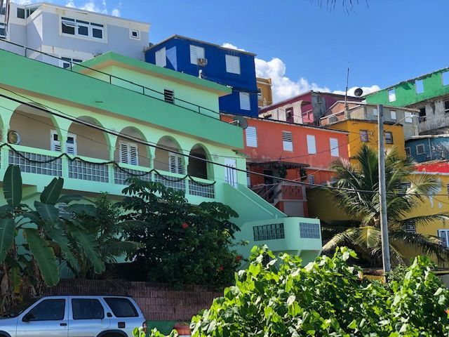 A car is parked in front of a row of colorful buildings