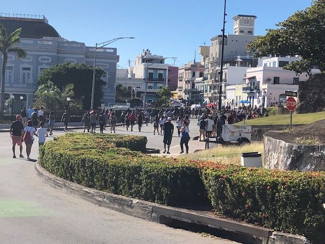 A group of people walking down a street with a stop sign in the background