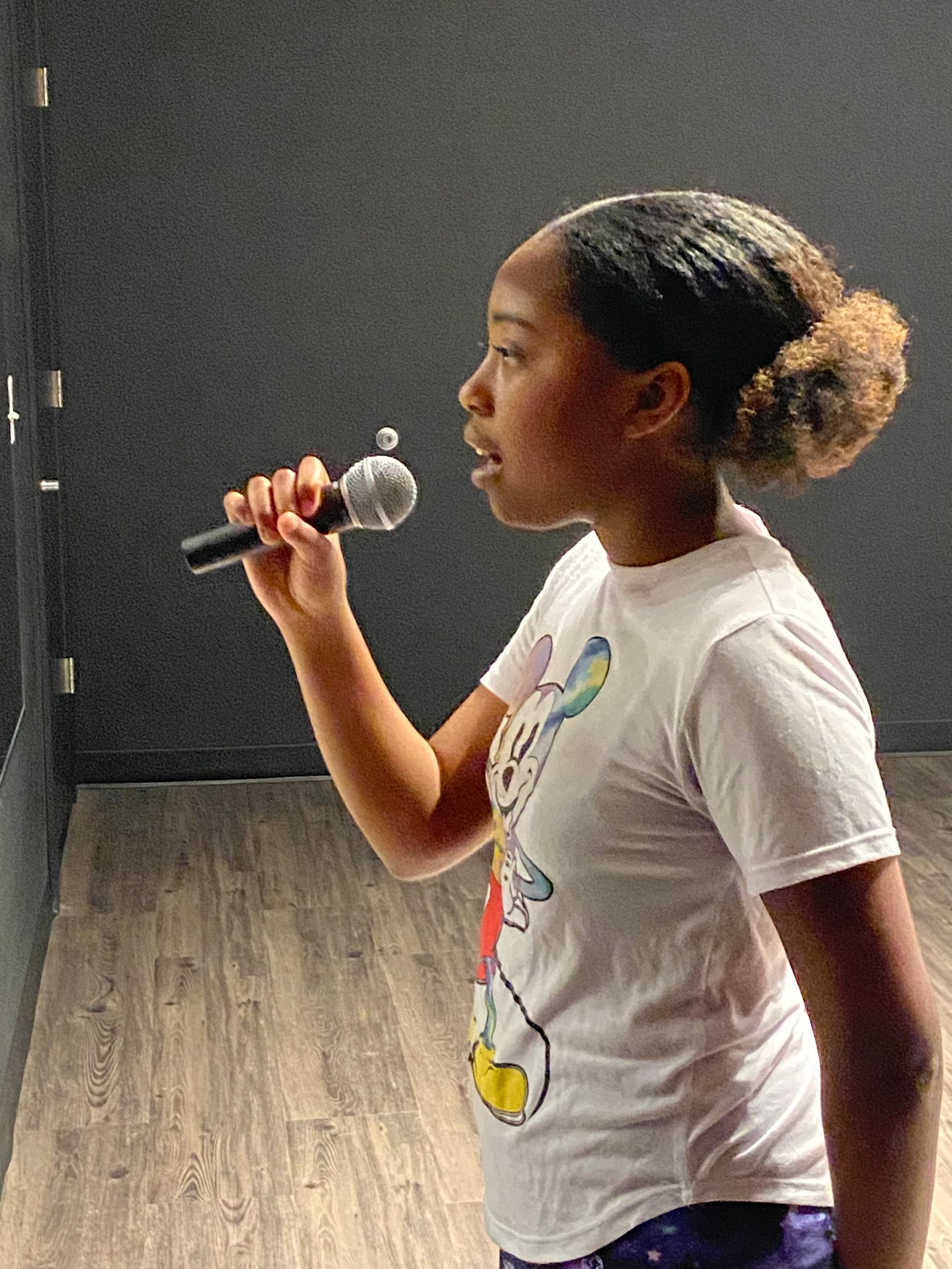 A young girl singing into a microphone in a room