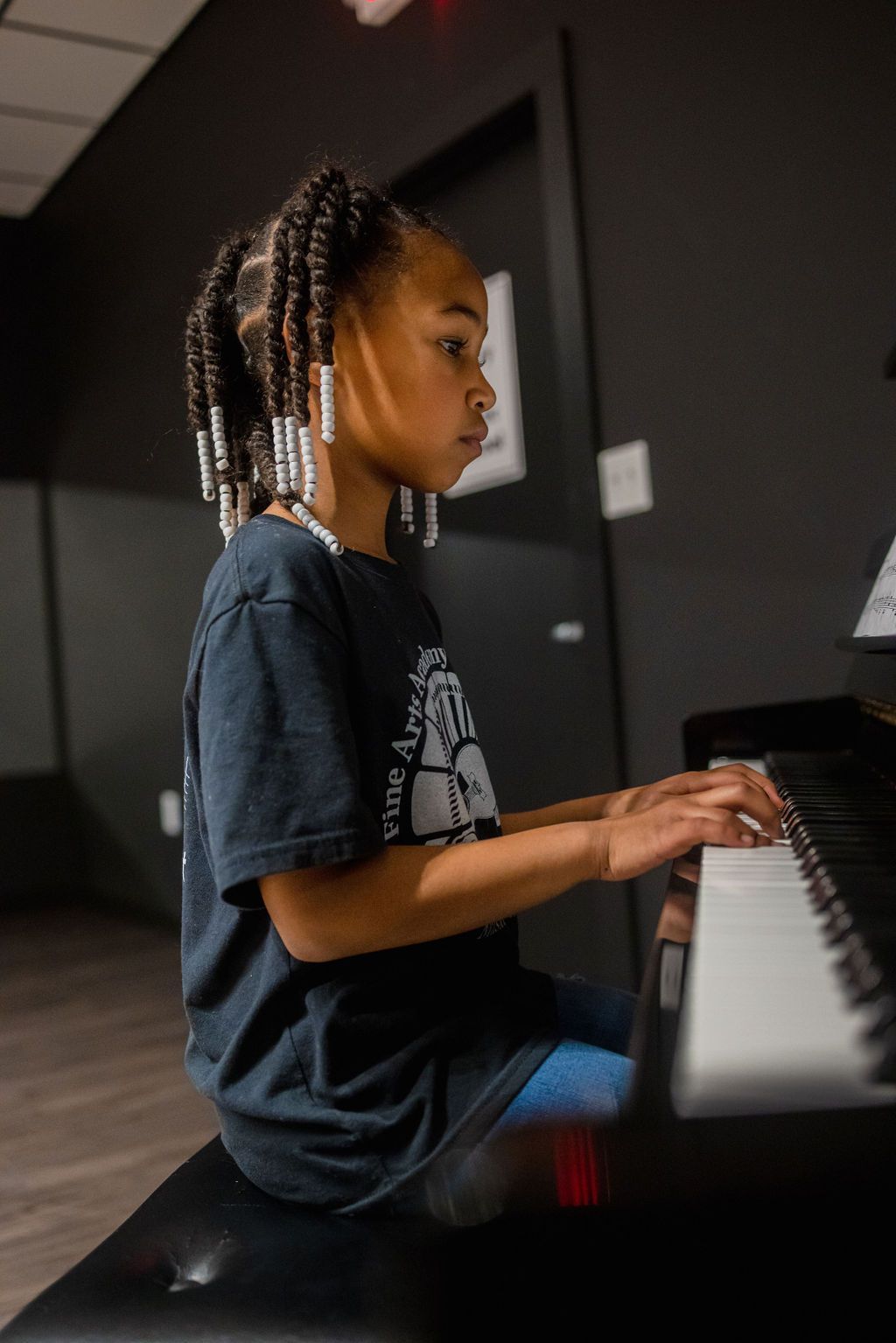 A young girl is sitting on a bench playing a piano.