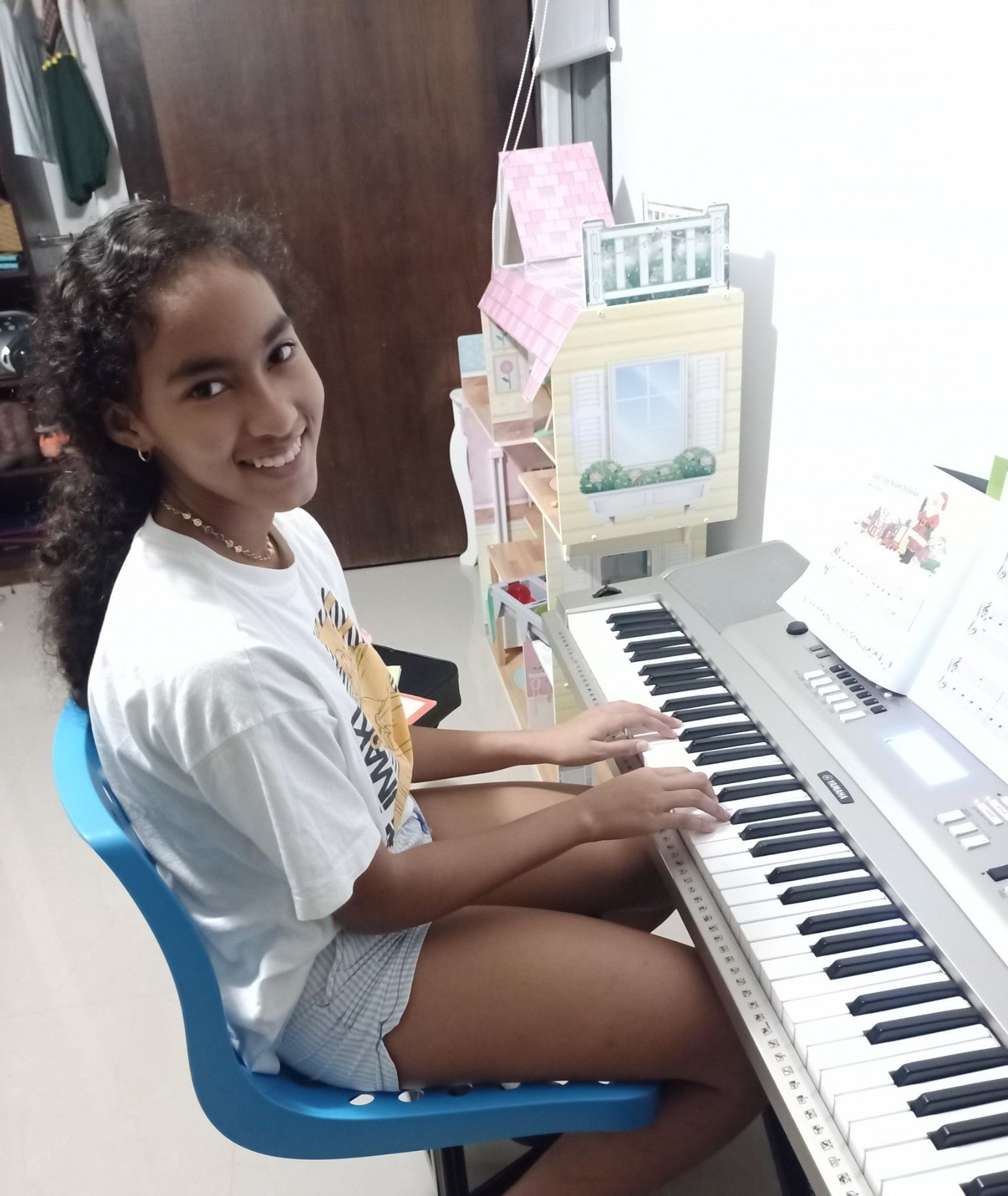 A young girl is sitting at a piano and smiling