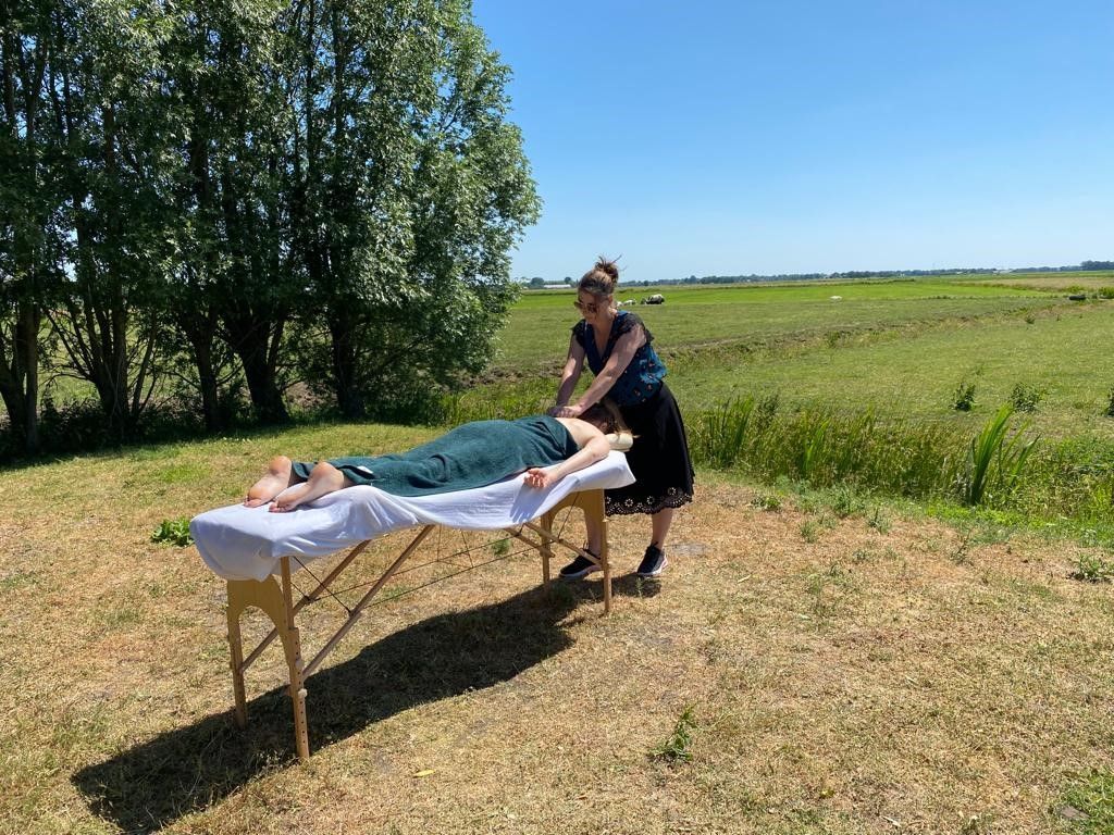 Een massagetherapeut geeft een massage in de buitenlucht op een zonnige dag.