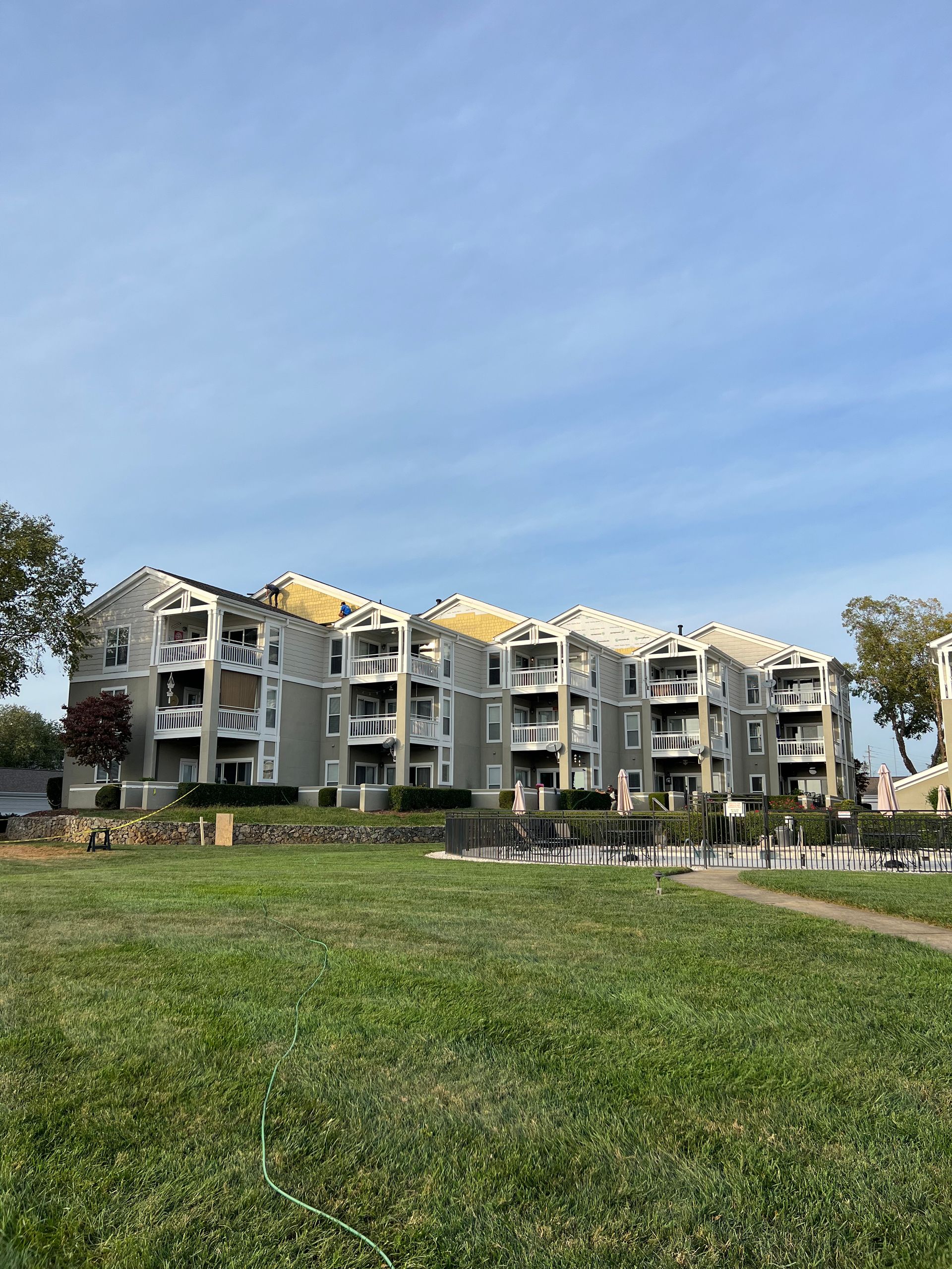 A large apartment building with a lush green field in front of it.