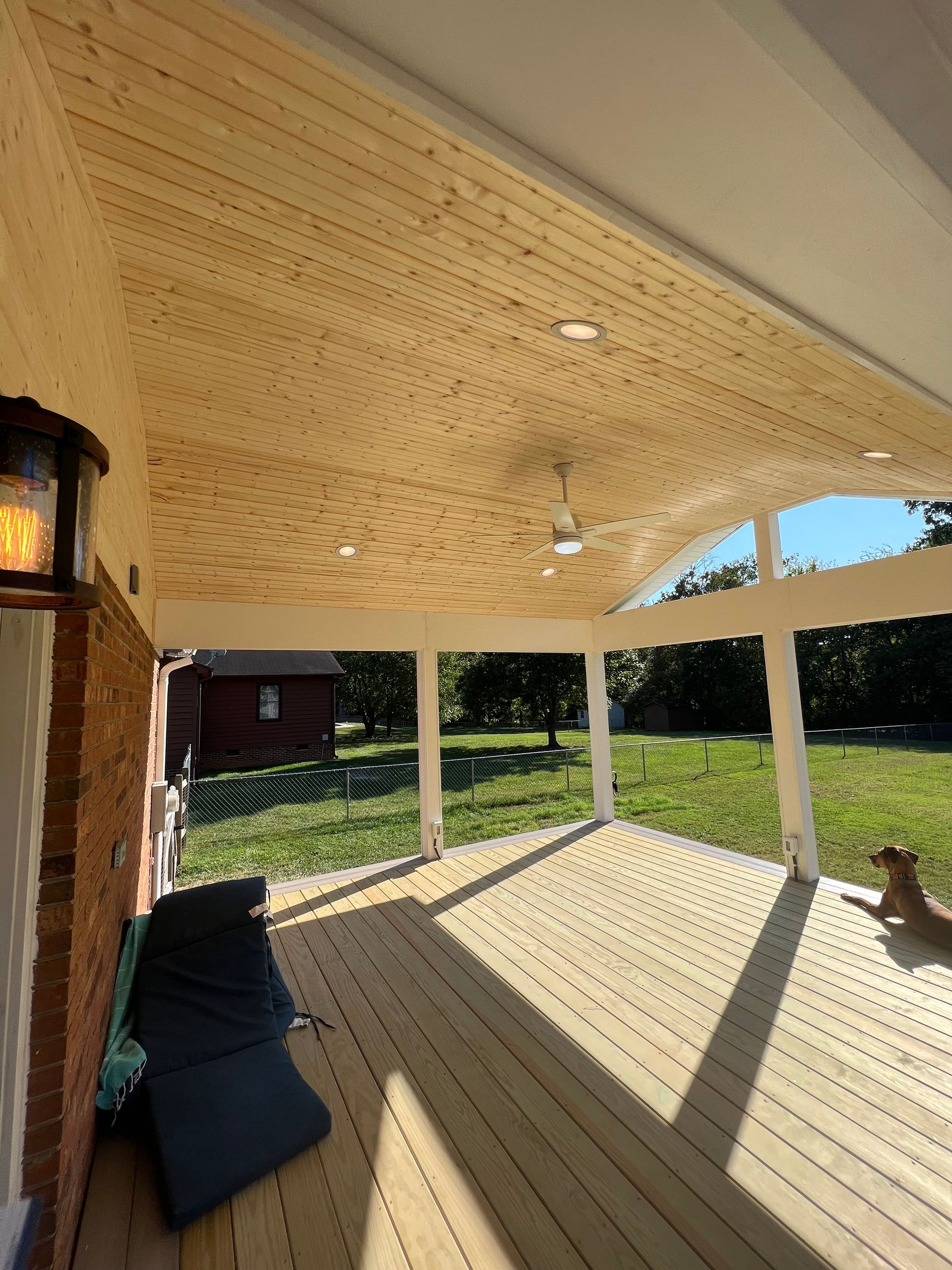A wooden deck with a ceiling fan and a dog on it