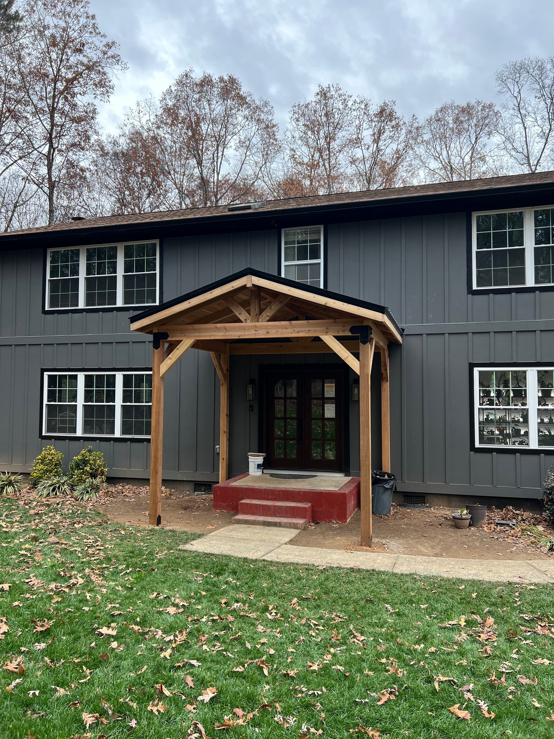 A large gray house with a wooden porch on the front of it.