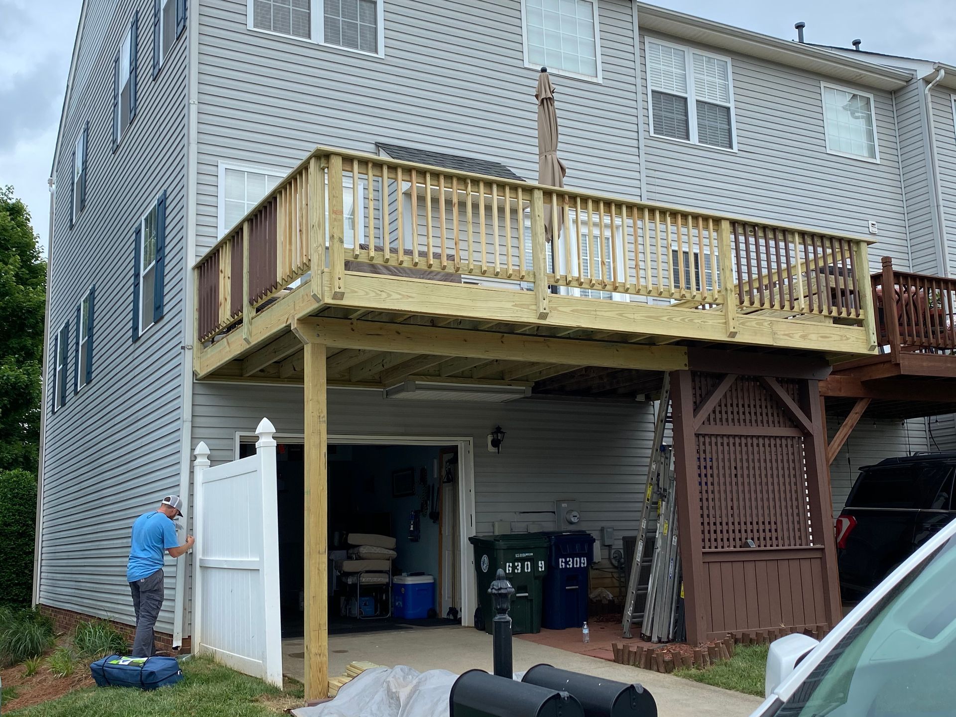 A man is standing in front of a house with a wooden deck.