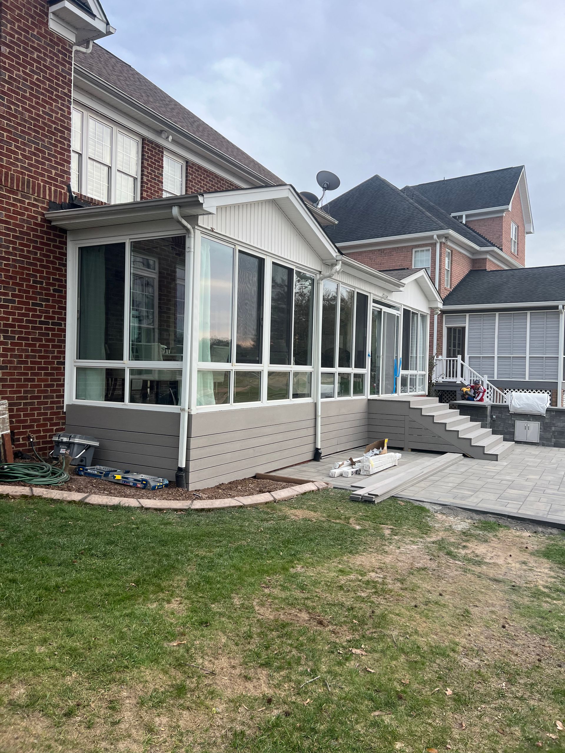 A sun room is being built on the side of a brick house.