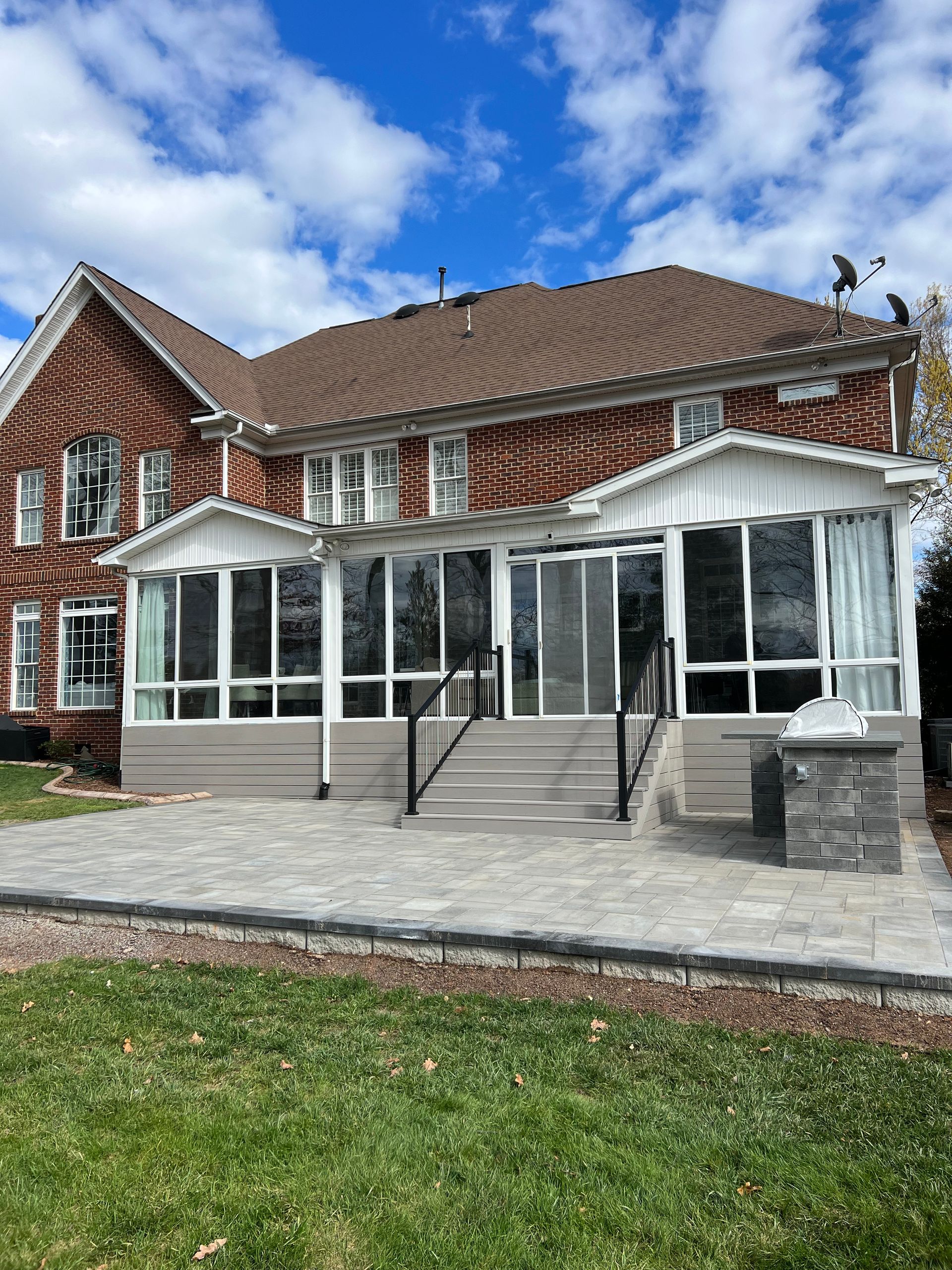 A large brick house with a large sunroom and a patio.