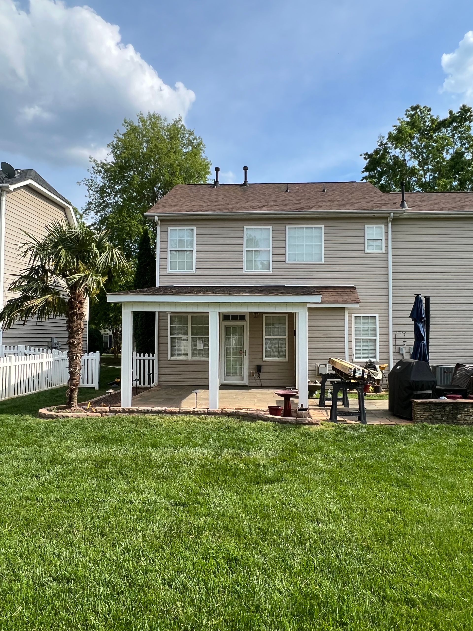 The backyard of a house with a large lawn and a porch.