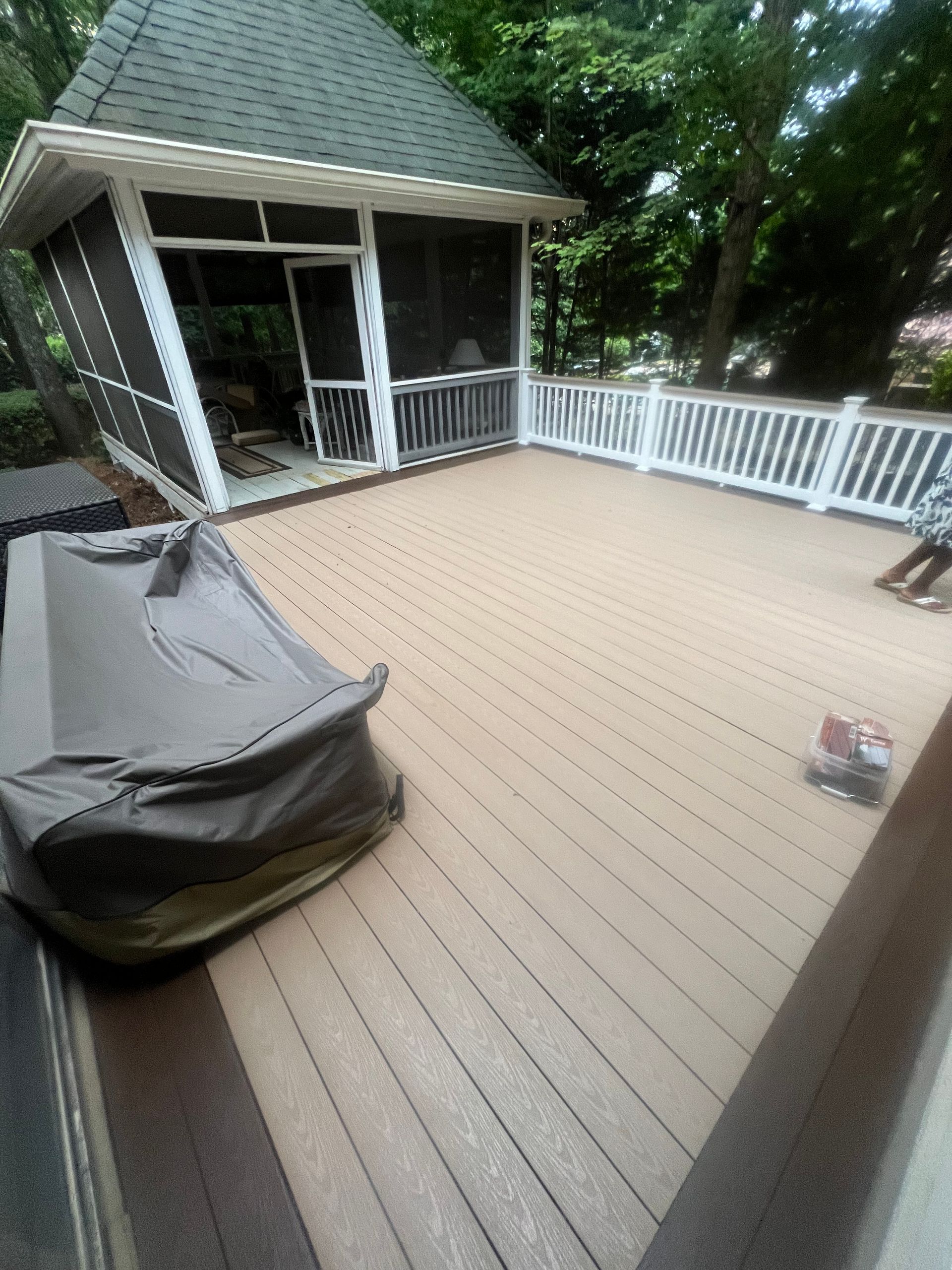 A screened in porch with a wooden deck and a gazebo.