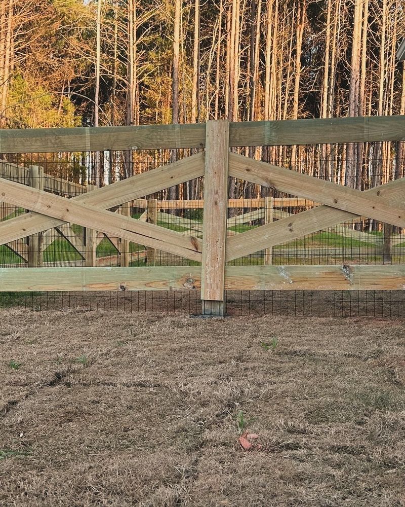 Wooden fence with an X-pattern design, set in a yard, trees in the background.