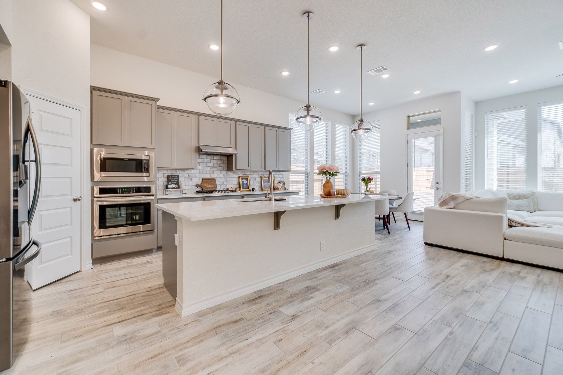 Bright modern open-plan kitchen and living room with white cabinets, island, and light wood floors