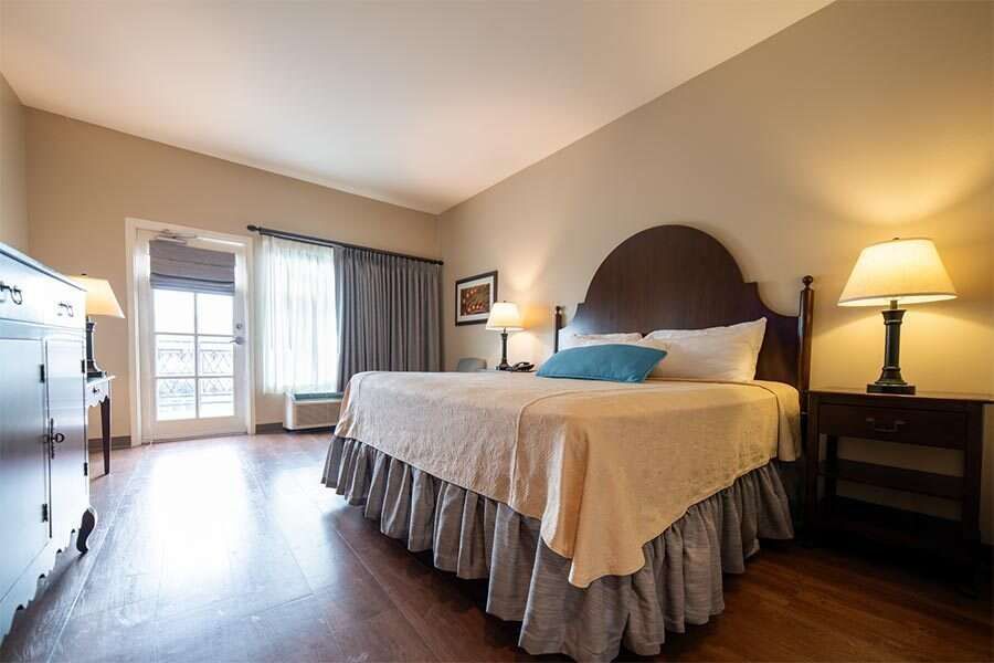 Hotel room with a bed, bedside tables, and a balcony door.