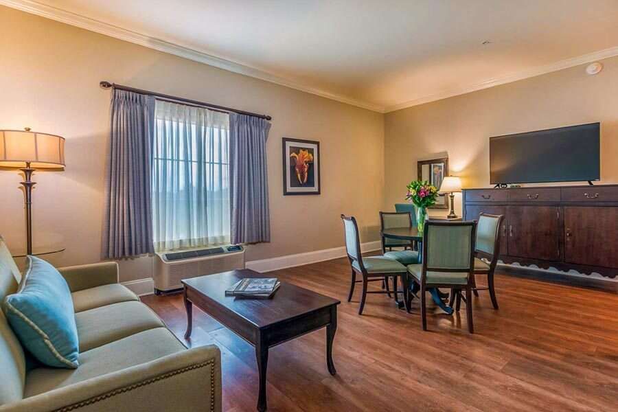 Living room with a sofa, dining table, TV, and window with blue curtains.