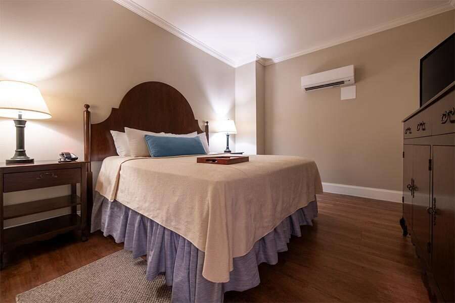 Bedroom with a double bed, bedside tables, a dresser, and air conditioning unit.